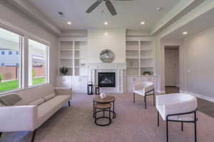 Living area featuring a ceiling fan, built in shelves, a glass covered fireplace, recessed lighting, and baseboards
