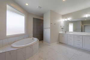 Bathroom featuring a garden tub, vanity, marble finish flooring, recessed lighting, and baseboards