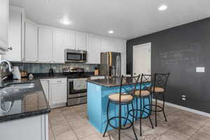 Open kitchen featuring granite countertop, stainless steel appliances and white cabinets
