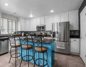 Open kitchen featuring granite countertop, stainless steel appliances and white cabinets