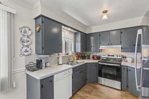 Kitchen with electric range, a sink, dishwasher, ornamental molding, and gray cabinets