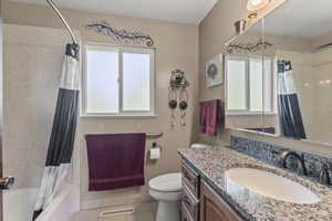 Full bathroom with tile patterned flooring, toilet, vanity, and shower / tub combo