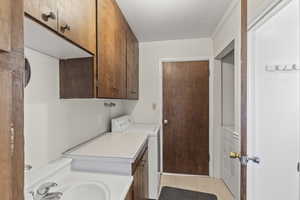 Clothes washing area featuring washer / clothes dryer and light tile patterned flooring