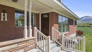 Entrance to property featuring brick siding, a mountain view, and covered porch
