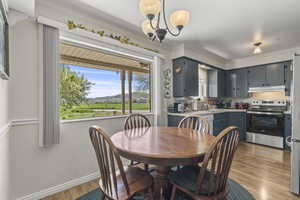Dining room with light wood-style flooring, crown molding, a chandelier, and baseboards