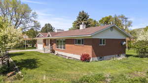 View of front facade with a garage, a front lawn, a chimney, and driveway