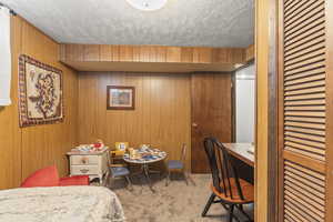 Carpeted bedroom featuring wooden walls and a textured ceiling
