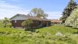Rear view of property with entry steps, a chimney, brick siding, and a yard