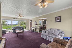 Carpeted living room featuring a ceiling fan, ornamental molding, a chandelier, a textured ceiling, and baseboards