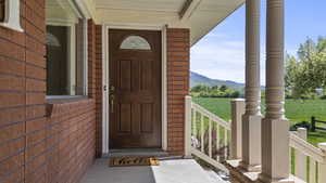 Doorway to property with brick siding, a porch, and a mountain view
