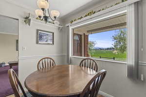 Dining space featuring baseboards, a chandelier, and crown molding