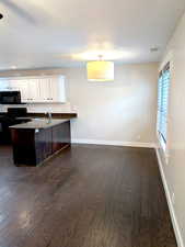 Kitchen with black appliances, dark wood-style flooring, a sink, a peninsula, and dark countertops