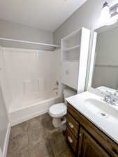 Bathroom featuring toilet, vanity, shower / tub combination, a textured ceiling, and baseboards