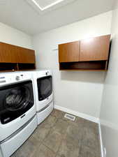 Washroom featuring independent washer and dryer, baseboards, and cabinet space