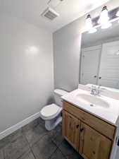 Half bathroom with toilet, vanity, a textured ceiling, and baseboards