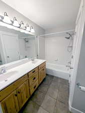 Master Bathroom featuring a textured ceiling, double vanity, bathing tub / shower combination, and tile patterned floors