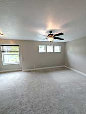 Master bedroom featuring a textured ceiling, carpet flooring, ceiling fan, and baseboards
