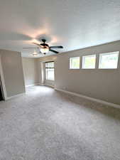 Bedroom featuring a textured ceiling, baseboards, a ceiling fan, and light carpet