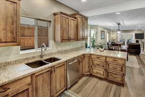 Kitchen with stainless steel dishwasher, a sink, wood finished floors, a peninsula, and recessed lighting