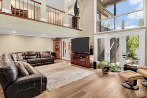 Living area featuring a towering ceiling, wood finished floors, recessed lighting, and french doors