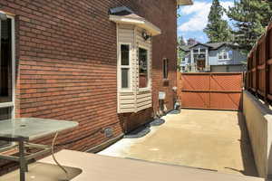 View of property exterior with brick siding, a patio, and fence