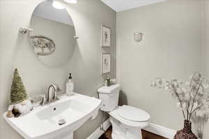 Bathroom featuring toilet, wood finished floors, a sink, and baseboards