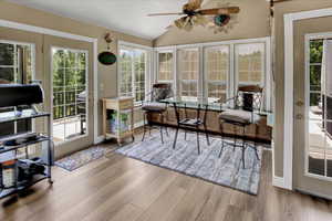 Sunroom featuring wood finished floors, lofted ceiling, baseboards, and french doors
