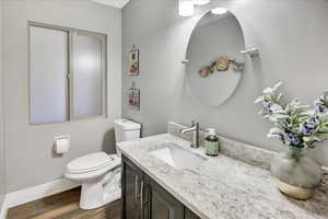 Bathroom with toilet, wood finished floors, vanity, and baseboards