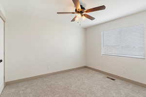Spare room with light carpet, a ceiling fan, and baseboards