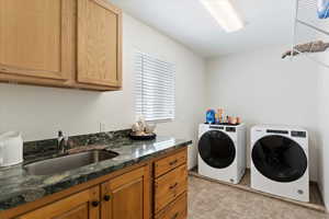 Clothes washing area with cabinet space, washer and clothes dryer, and light tile patterned floors
