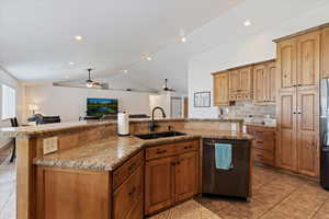 Kitchen featuring appliances with stainless steel finishes, a sink, a ceiling fan, open floor plan, and lofted ceiling