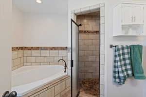 Full bathroom with a stall shower, a bath, and recessed lighting