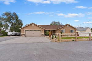 Ranch-style home featuring stone siding, a garage, stucco siding, and driveway