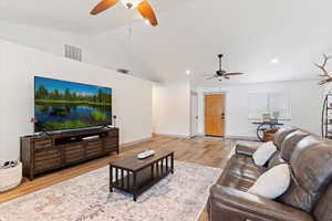 Living area featuring a ceiling fan, vaulted ceiling, wood finished floors, baseboards, and recessed lighting