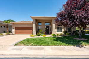 View of front facade featuring stucco siding, a garage, a front lawn, concrete driveway, and a tile roof