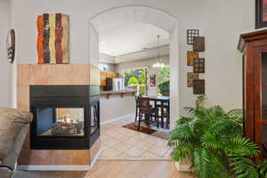 Hallway with baseboards, light wood-style flooring, a chandelier, ornamental molding, and arched walkways