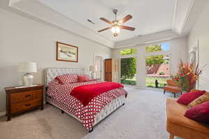 Bedroom with a tray ceiling, carpet, and ceiling fan