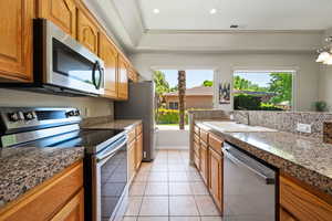 Kitchen with appliances with stainless steel finishes, a sink, healthy amount of natural light, brown cabinets, and recessed lighting
