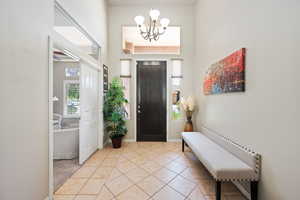 Foyer entrance with a chandelier, a high ceiling, light tile patterned floors, and baseboards