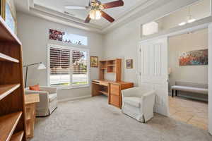 Sitting room featuring a ceiling fan, a towering ceiling, an office area, a raised ceiling, and light carpet