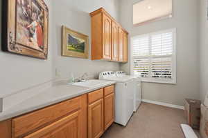 Laundry room with cabinet space, washer and dryer, light carpet, and baseboards