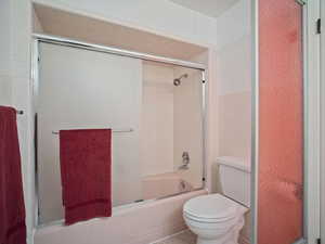 Full bathroom with toilet and enclosed tub / shower combo
