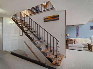 Staircase featuring carpet floors and a textured ceiling