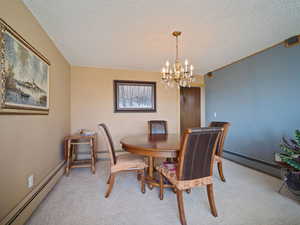 Dining room with a chandelier, a textured ceiling, a baseboard radiator, and light colored carpet