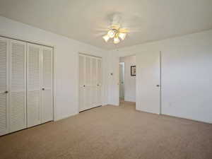 Unfurnished bedroom featuring multiple closets, carpet floors, ceiling fan, and baseboards