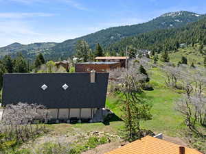 View of subject property featuring a mountain backdrop and a forest