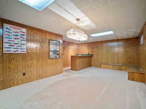 Unfurnished room featuring wooden walls and light carpet
