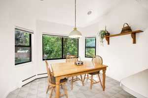 Dining room with baseboard heating, vaulted ceiling, and light flooring
