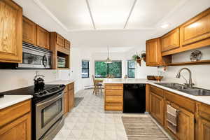 Kitchen with stainless steel appliances, a sink, open shelves, and brown cabinets