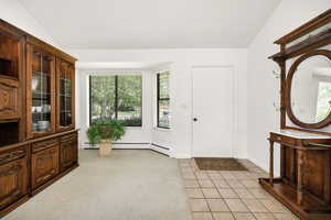 Foyer entrance with lofted ceiling, light tile patterned flooring, and baseboards